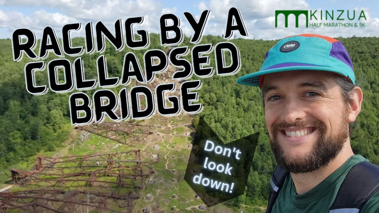 A smiling man wearing a colorful cap and running gear, with a collapsed bridge and lush green forest in the background. Text overlay reads 'RACING BY A COLLAPSED BRIDGE' and 'Don't look down!'.
