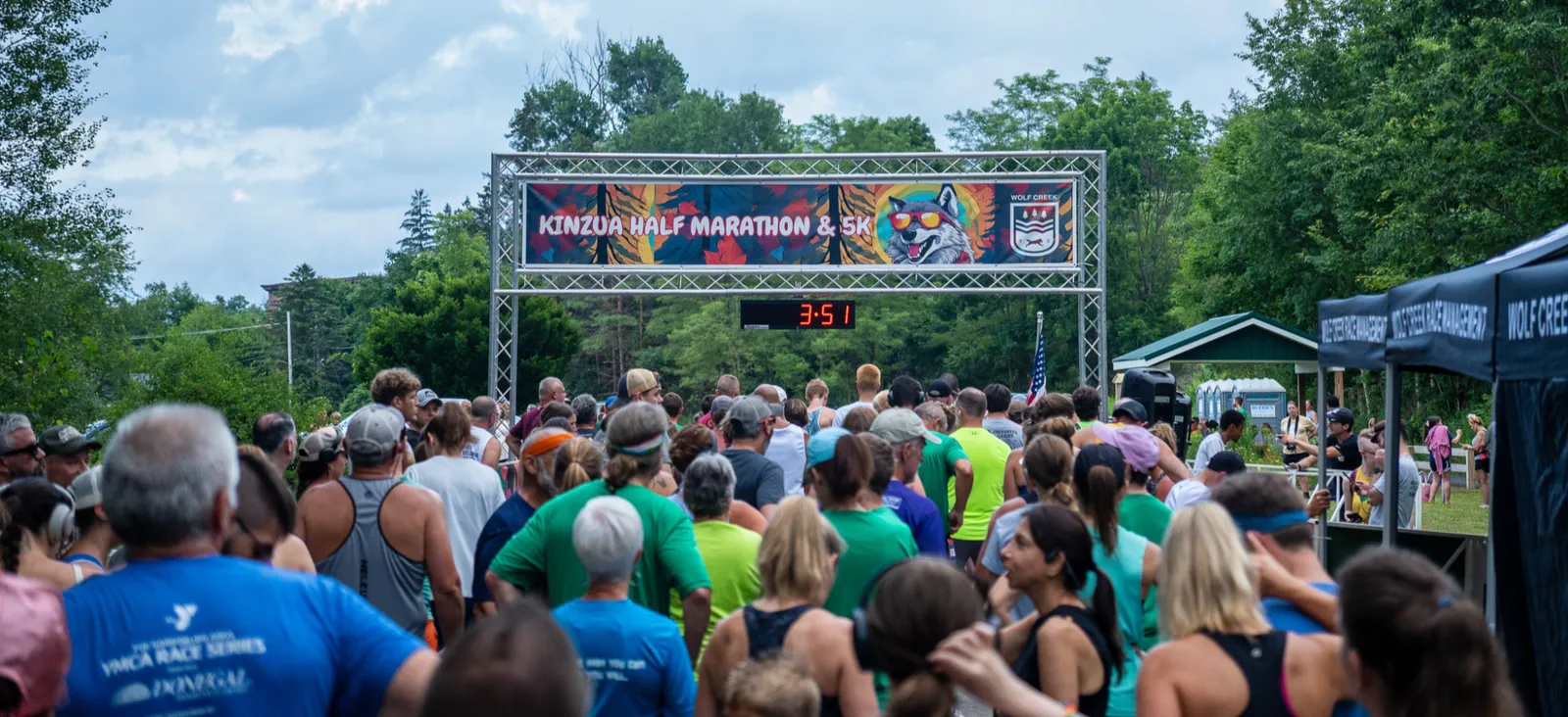 A large crowd of runners gathered at the start line under a banner that reads 'KINZUA HALF MARATHON & 5K'.