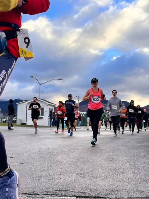 A group of runners starting a race, with the lead runner in a pink top and bib number 523.