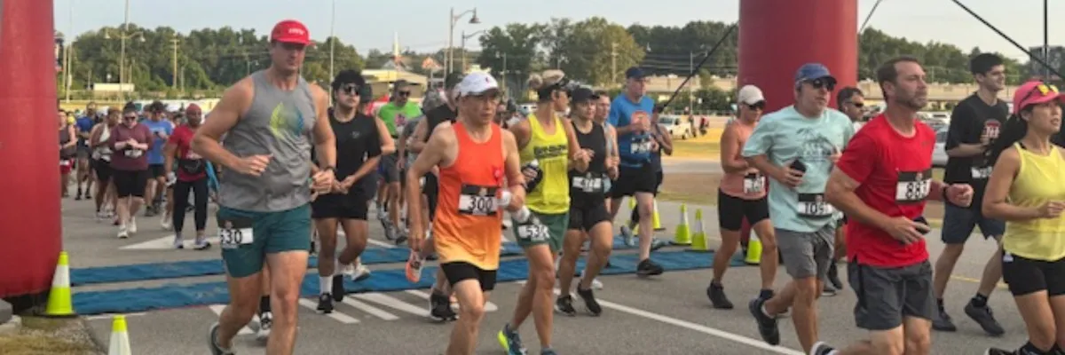 A group of runners starting a race, with some in the foreground and more in the background, under a red archway.