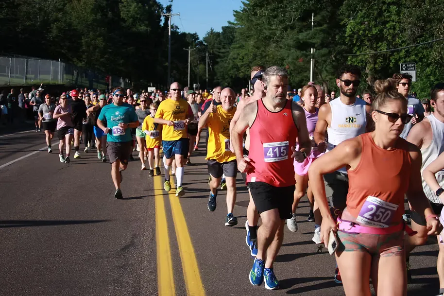 A group of runners in a race, with the lead runners in focus on a sunny day.