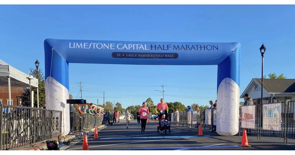 Runners crossing the start/finish line under the Limestone Capital Half Marathon arch.