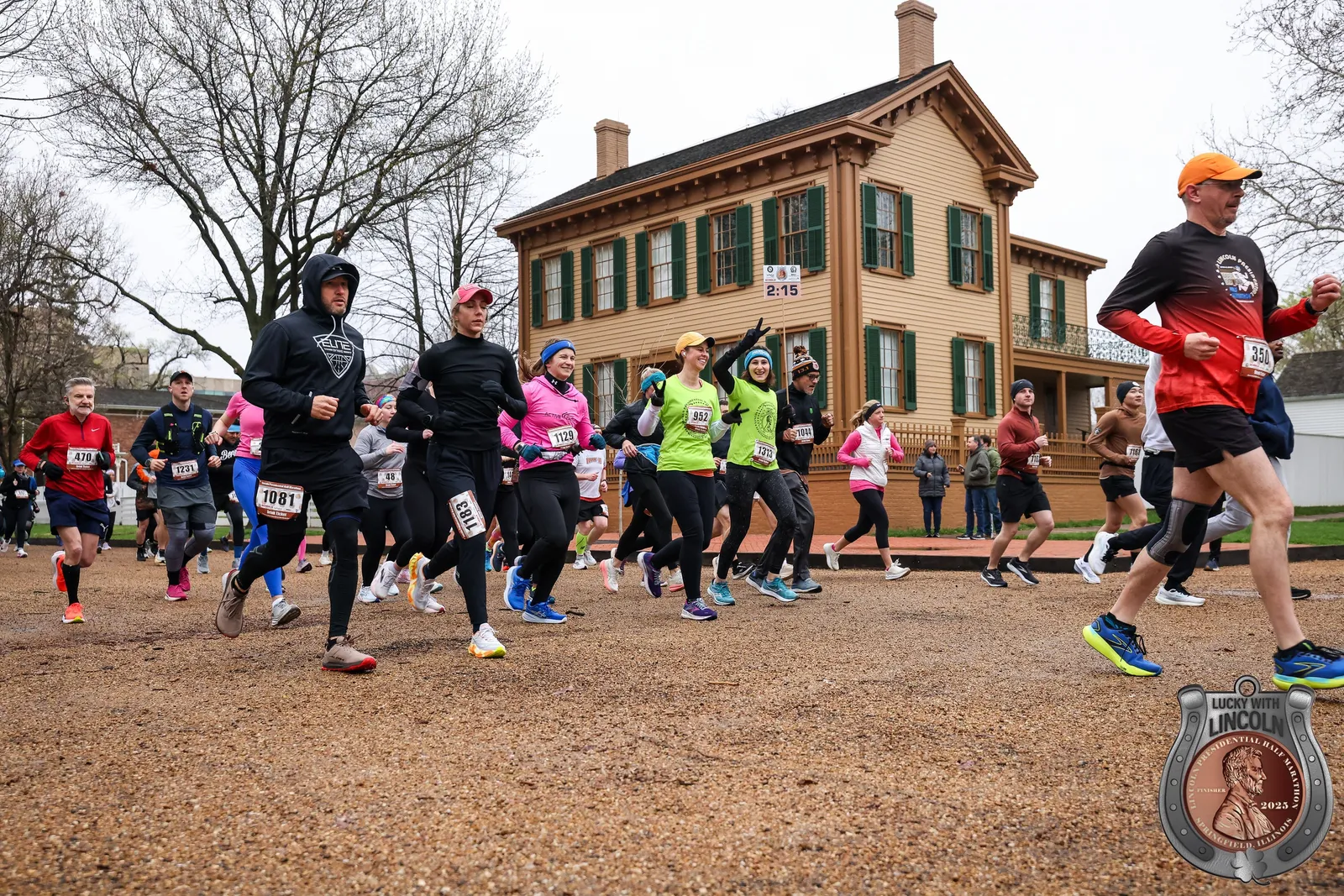 Runners in action at the start of the Lincoln Presidential Half Marathon, with a historic building in the background.