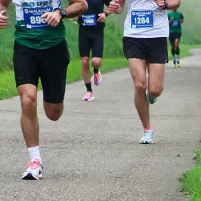 Runners on a paved path during a race, with bib numbers visible.