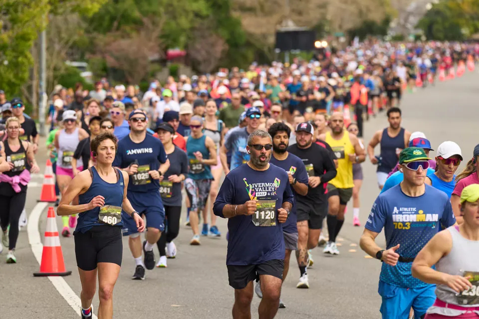A large group of runners participating in a half marathon, with a focus on a female runner in the foreground.