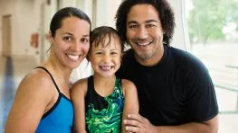 A smiling family of three, two adults and a child, pose for a photo.