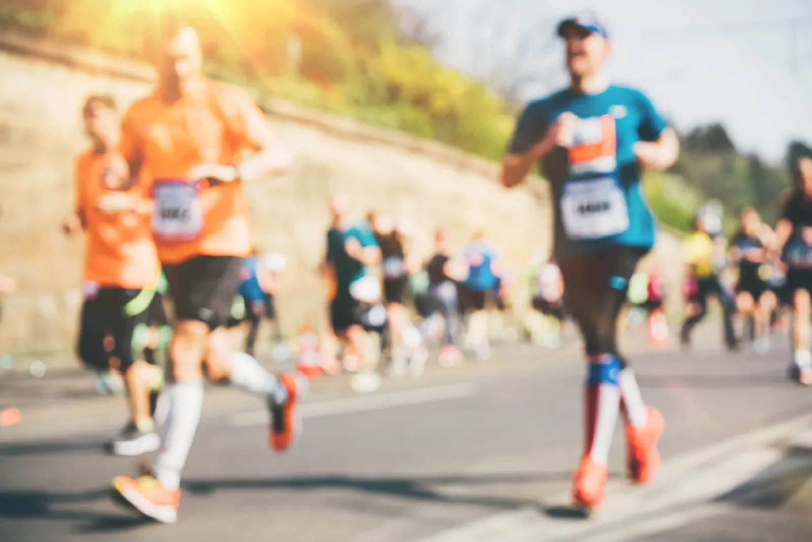 Runners in a race, with a focus on their legs and feet as they run on a road. The image is slightly blurred, giving a sense of motion.