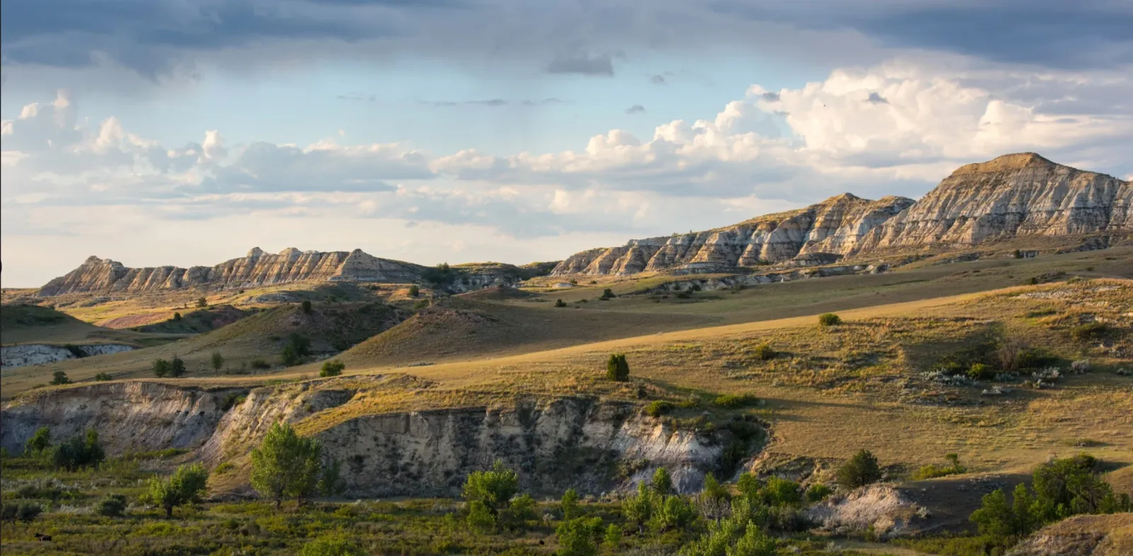 Scenic view of rolling hills and mountains with a dramatic sky, suggesting a trail running environment.