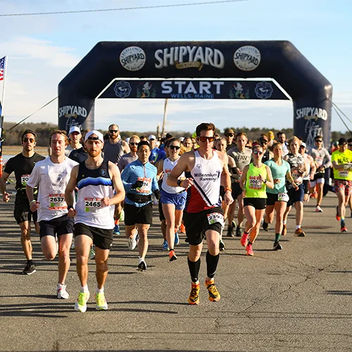 Runners starting the Maine Coast Half Marathon and 5K under an inflatable archway.