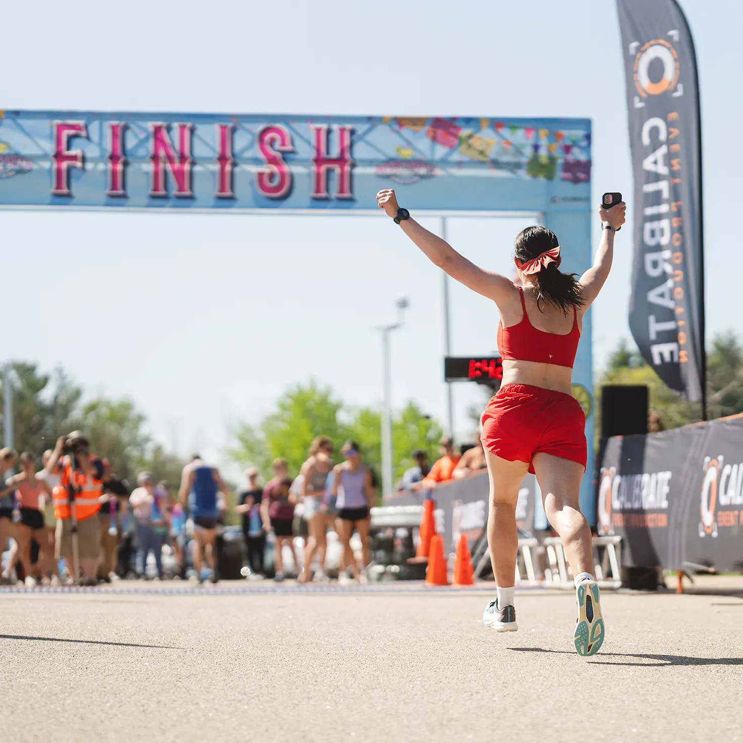 A runner celebrates as they cross the finish line at a road race.