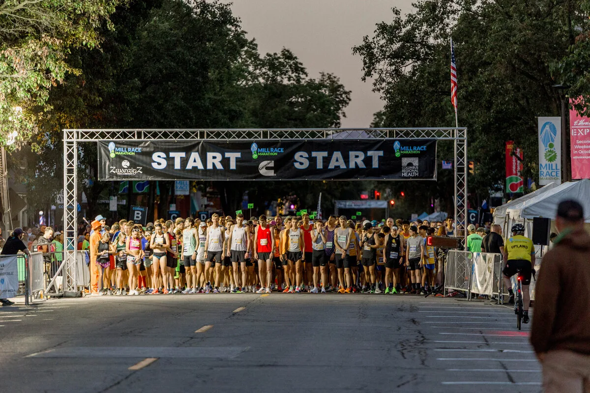 A large group of runners gathered at the start line under a banner that reads 'START'.