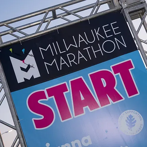 Milwaukee Marathon start line banner with large pink text reading 'START'.