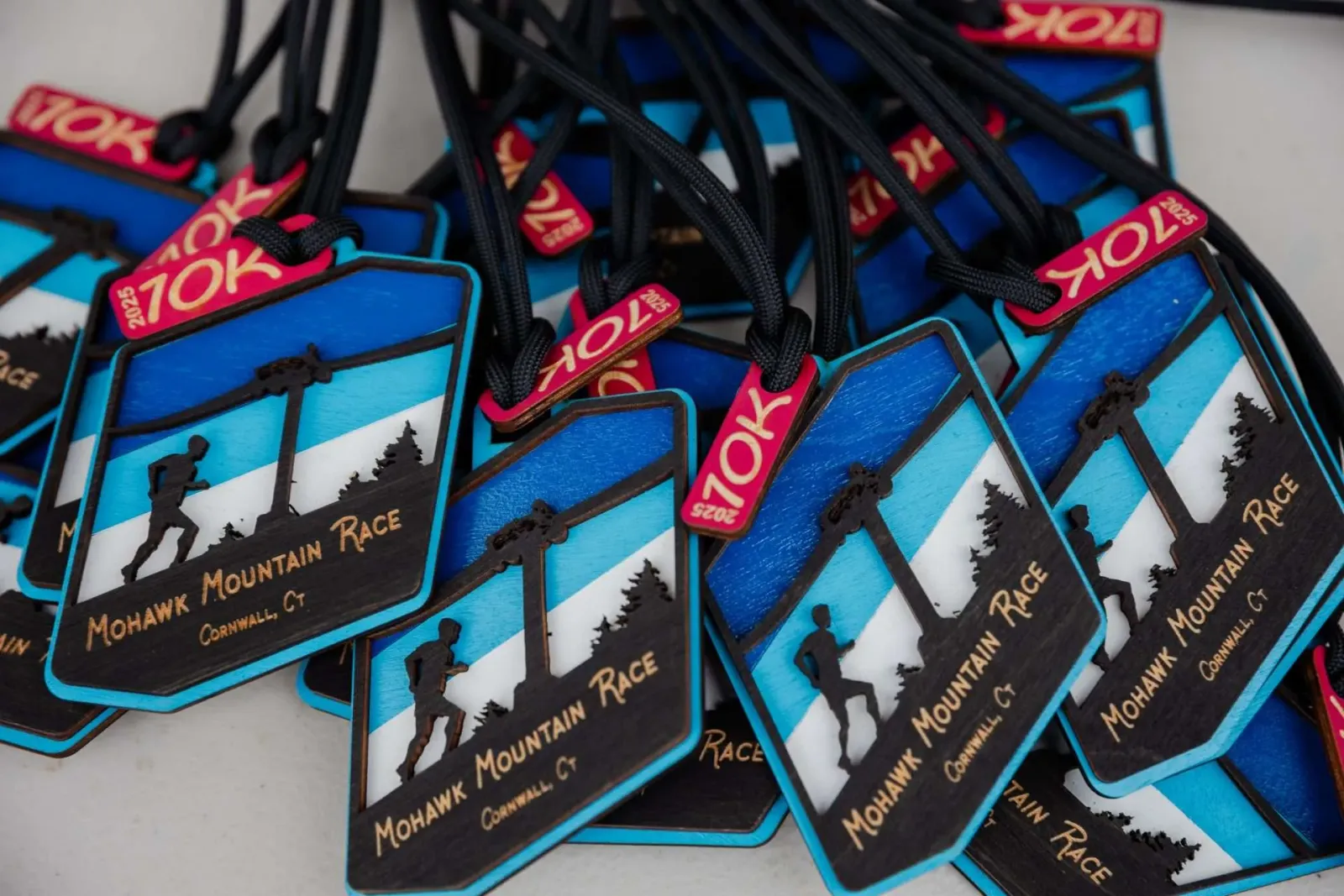 A pile of Mohawk Mountain Race medals, each featuring a silhouette of a runner on a mountain path.