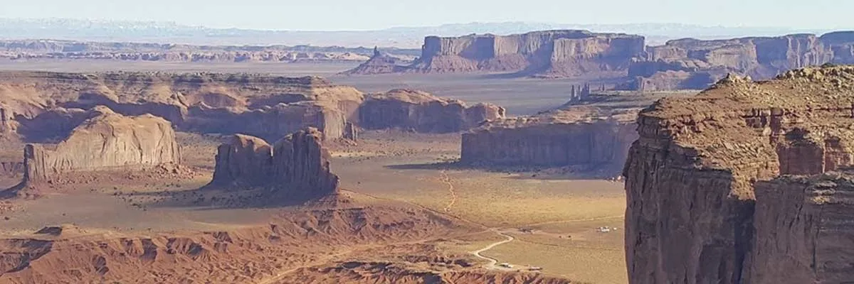 Panoramic view of Monument Valley with mesas and buttes under a clear sky.