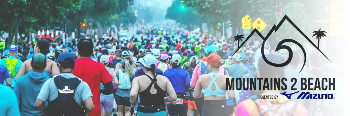 A large group of runners participating in the Mountains 2 Beach race, with race branding overlaid.