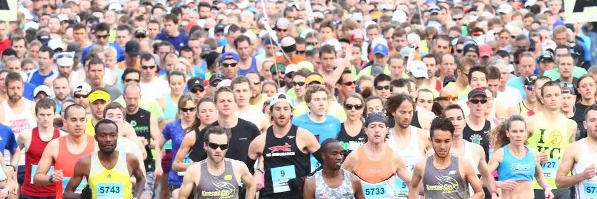 A large group of runners packed together at the start of a race, many looking forward with determination.