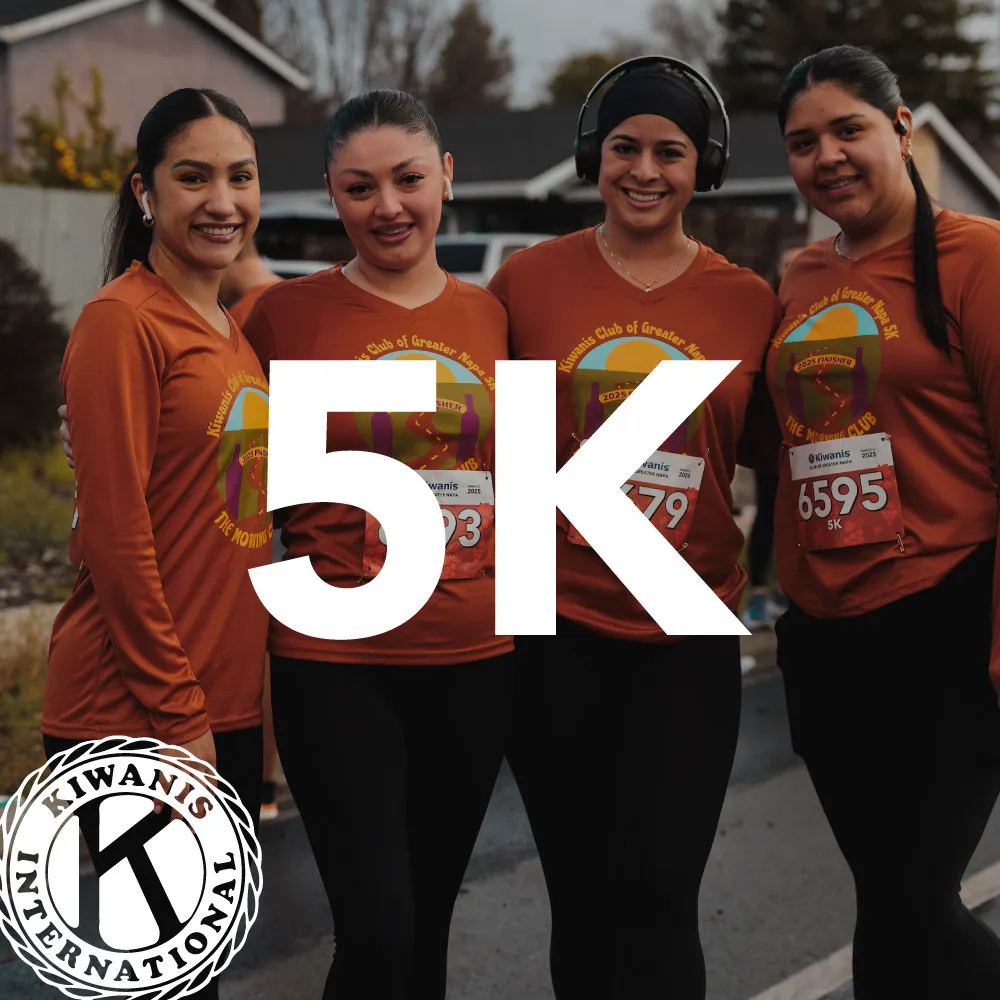 Four women smiling and posing for a photo, wearing matching race shirts and bibs, with large '5K' text overlay.