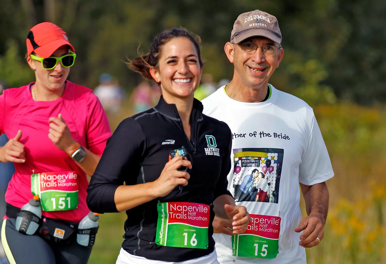 Three runners smiling and participating in the Naperville Trails Half Marathon.