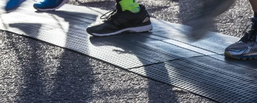 Close-up of runners' feet crossing a mat at the start line of a race.