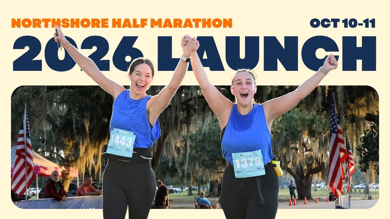 Two women with their arms raised in celebration, holding hands, at the Northshore Half Marathon launch event.
