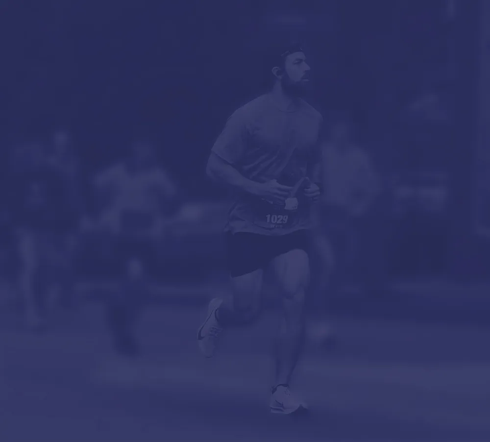 A male runner with bib number 1029 runs during a race, with other blurred runners in the background.