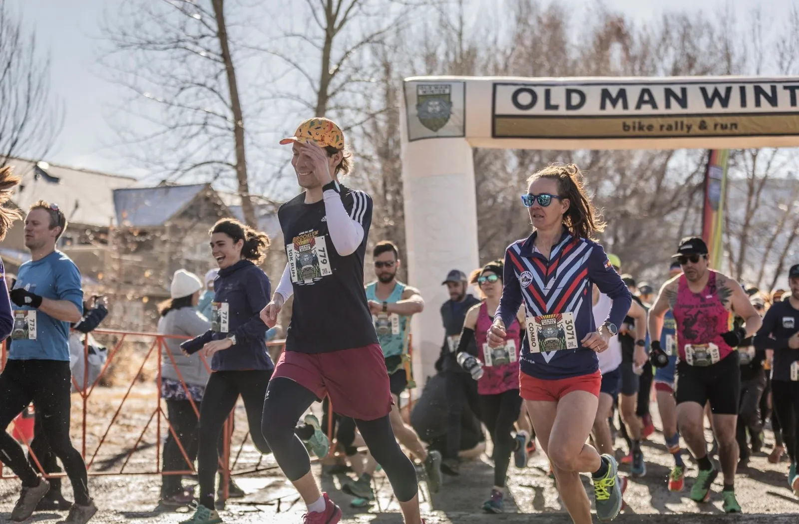Runners starting the Old Man Winter Bike Rally & Run race under a banner.