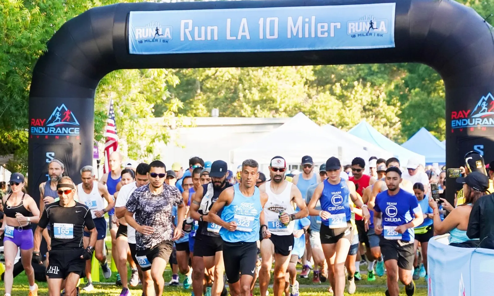 Runners at the start line of the Run LA 10 Miler race, passing under a large inflatable arch.