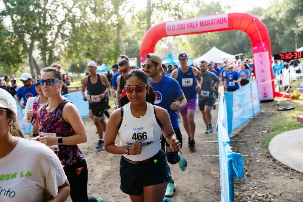 Runners starting the Old Zoo Half Marathon, passing under a red inflatable arch.