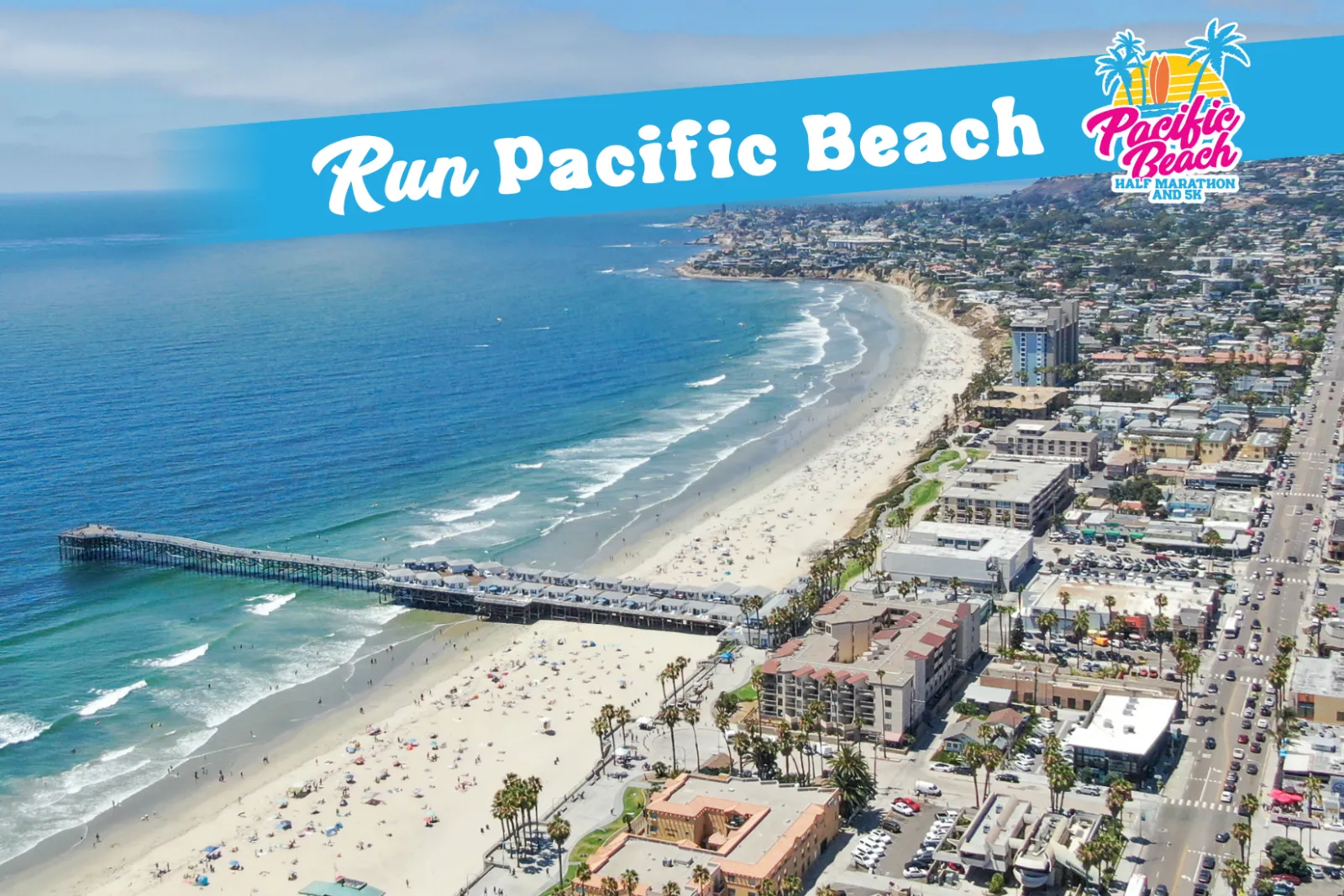 Aerial view of Pacific Beach with a pier and the ocean, featuring a banner that says 'Run Pacific Beach Half Marathon and 5K'.