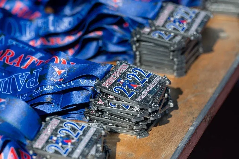 Stacks of Paine to Pain Trail Half Marathon medals from 2022 with blue lanyards.