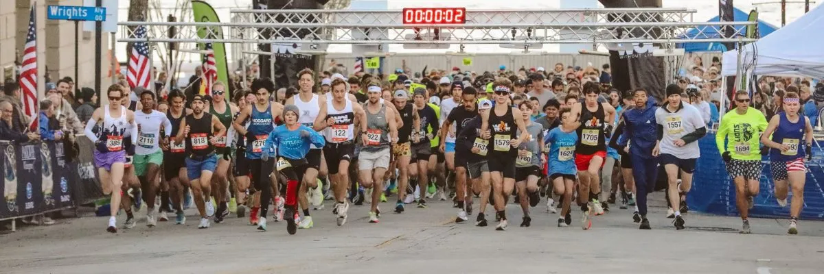A large group of runners are at the starting line of a race, with a digital clock showing 00:00:02 overhead.
