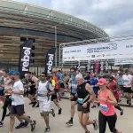 Runners starting the Perth Half Marathon with a stadium in the background.