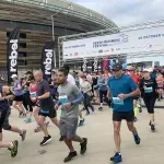Runners starting the Perth Half Marathon with a stadium in the background.