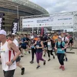 Runners starting the Perth Half Marathon WA, with a large banner overhead.