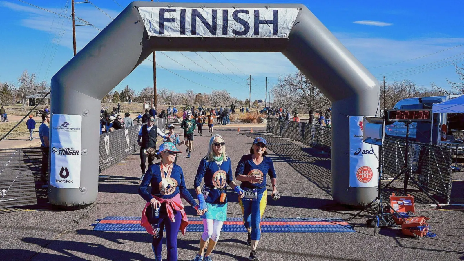 Runners crossing the finish line at the Platte River Half Marathon Relay 5K, with an inflatable arch overhead and spectators in the background.