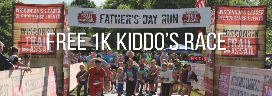 A group of children running towards the camera under a banner that reads 'Wisconsin Trail Assail Father's Day Run', with large white text overlaying the image that says 'FREE 1K KIDDO'S RACE'.