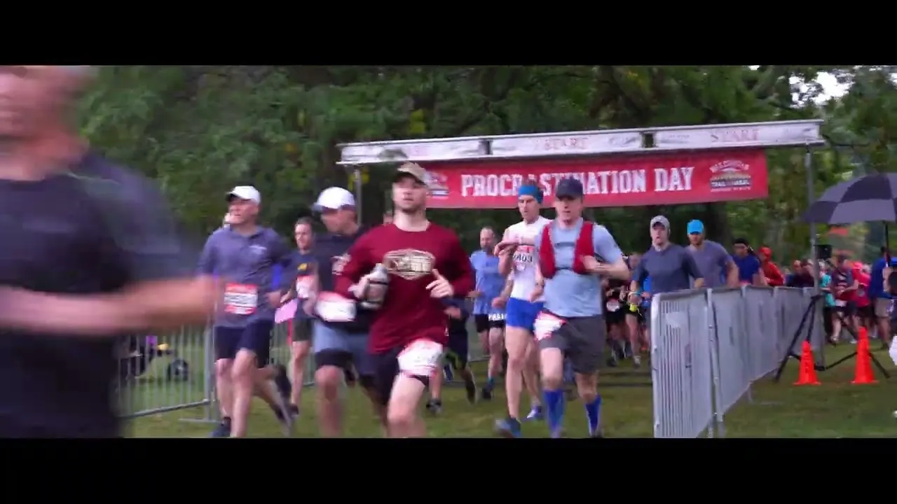 Runners starting a race under a banner that says 'Procrastination Day'.