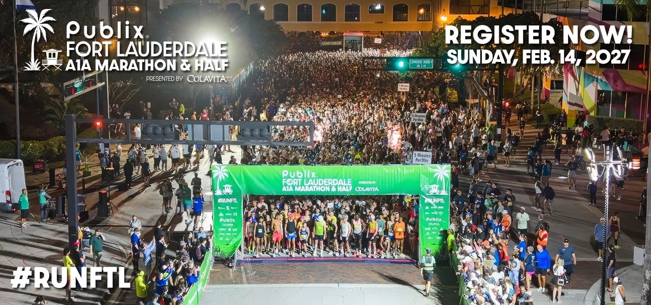 A large crowd of runners gathers at the start line of the Publix Fort Lauderdale Marathon & Half Marathon at night, with bright lights and banners.