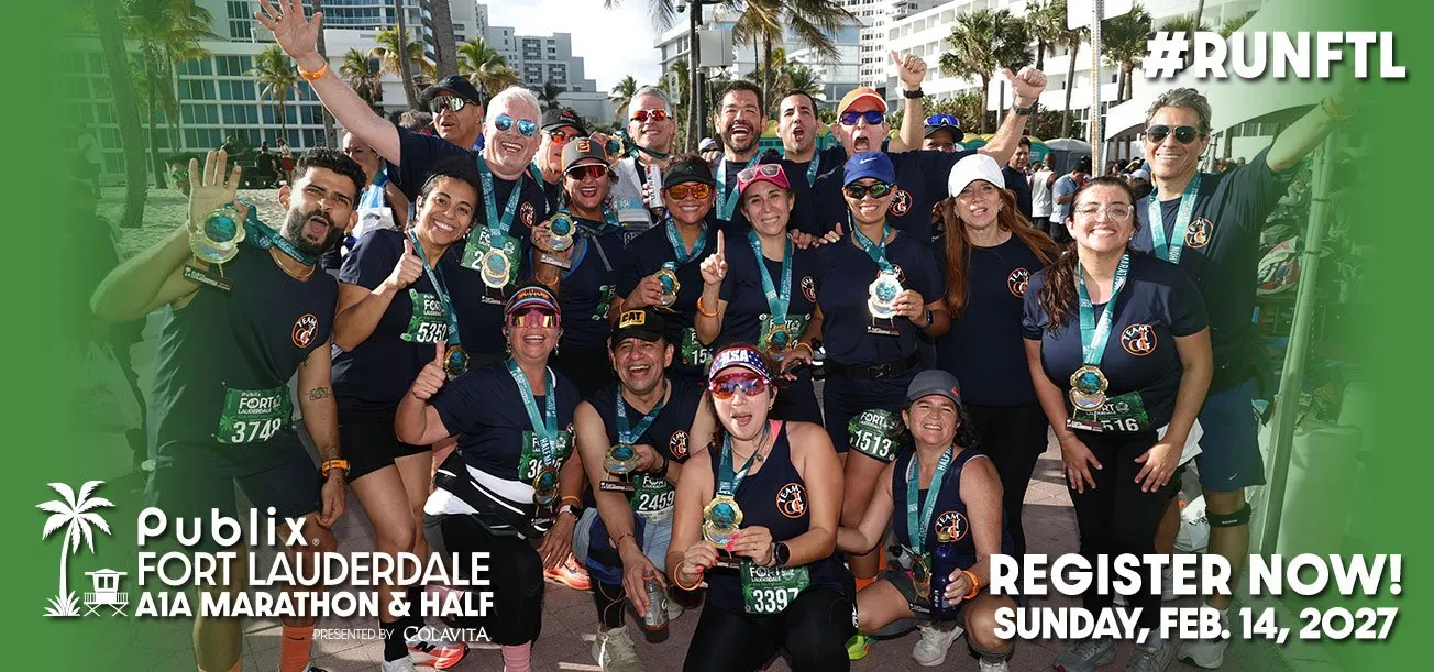 A large group of smiling runners, many wearing medals, pose for a photo after completing the Publix Fort Lauderdale A1A Marathon and Half Marathon.