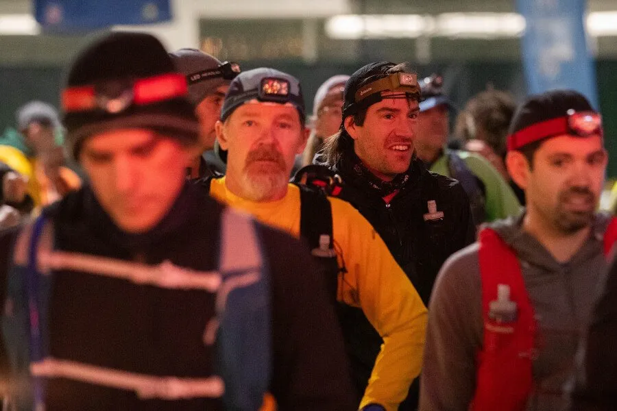 Runners wearing headlamps gather at the start of a race.