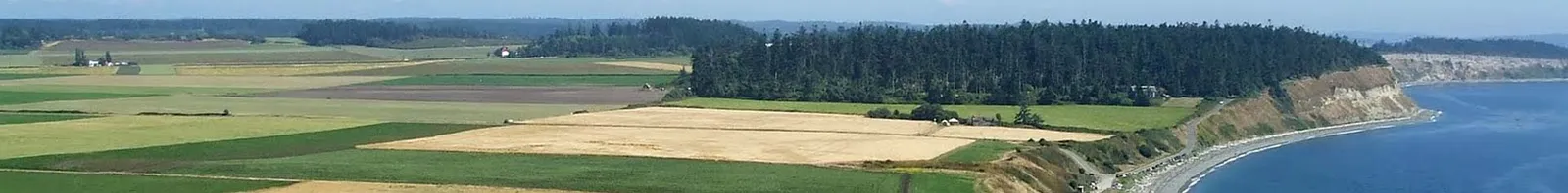 Panoramic view of farmland and coastal cliffs overlooking the water, likely part of the race course.