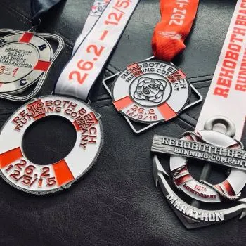 Four race medals from the Rehoboth Beach Marathon and Half Marathon, including a life preserver design and an anchor design.