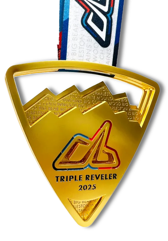 A close-up, golden triangular race medal with a mountain design and the text 'TRIPLE REVELER 2025'.