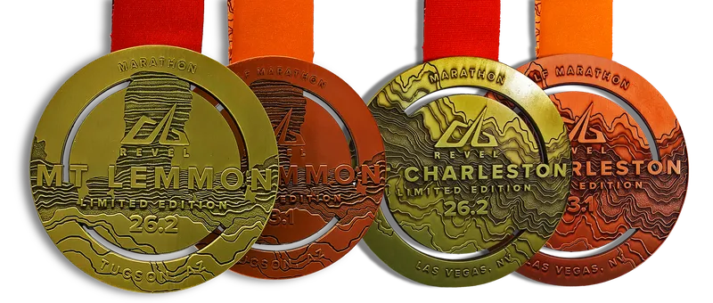 Four different Revel race medals displayed, featuring unique designs for Mt. Lemmon, Charleston, and other locations.