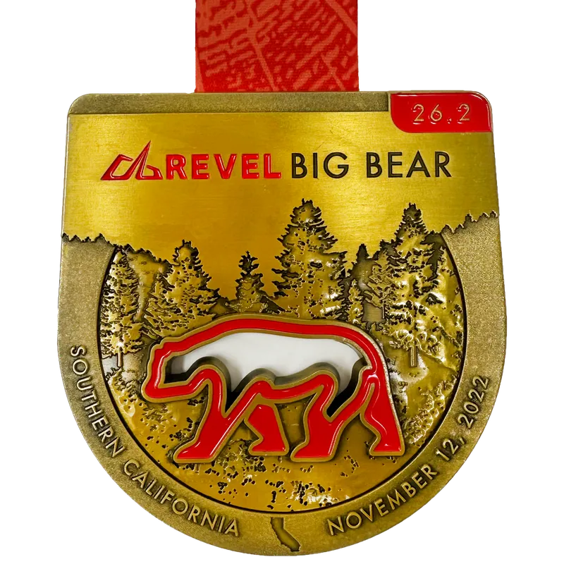 A gold medal for the Revel Big Bear race, featuring a bear graphic, pine trees, and text indicating 'Southern California November 12, 2022'.