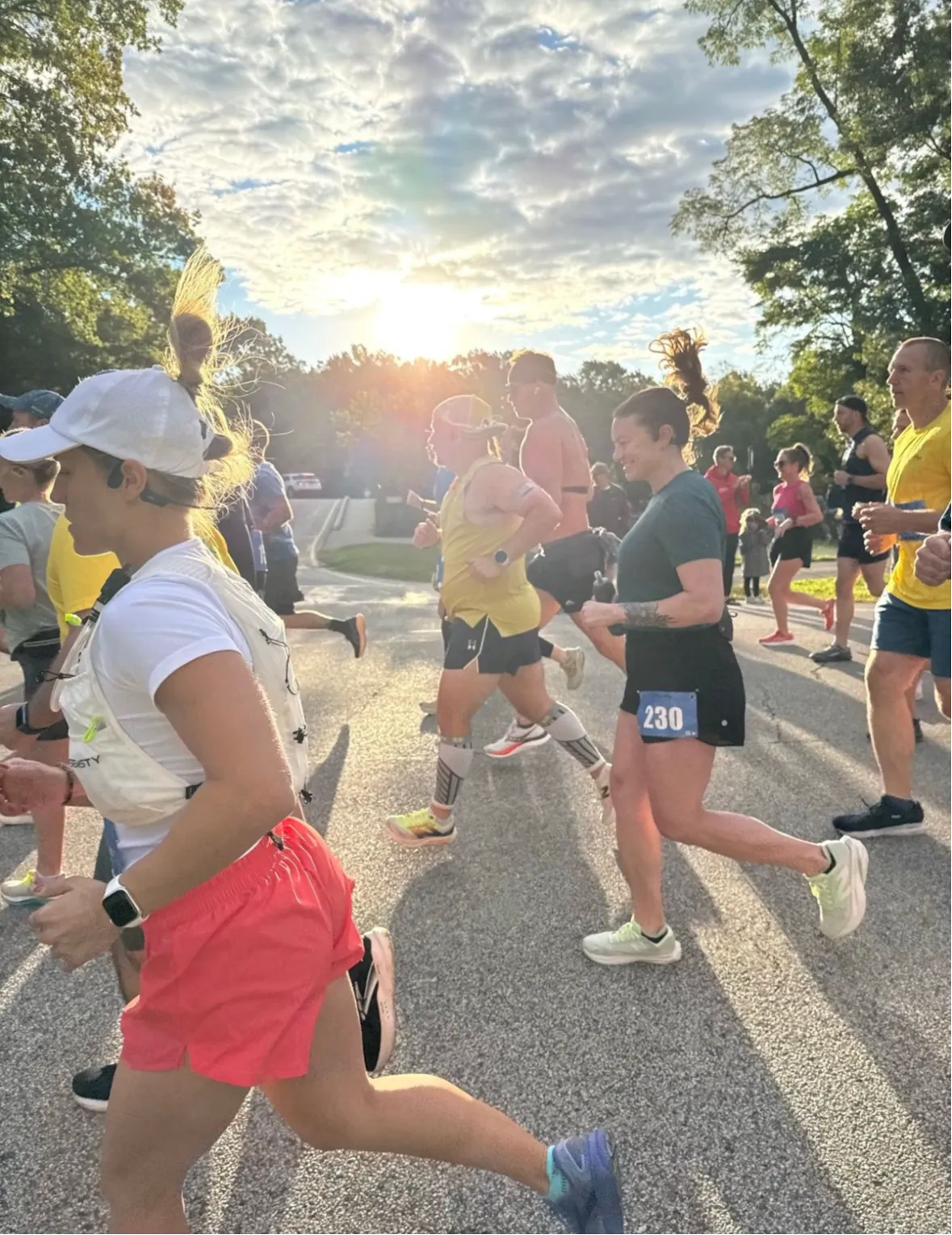 Runners in a race, with the sun setting behind them, capturing the start of the event.