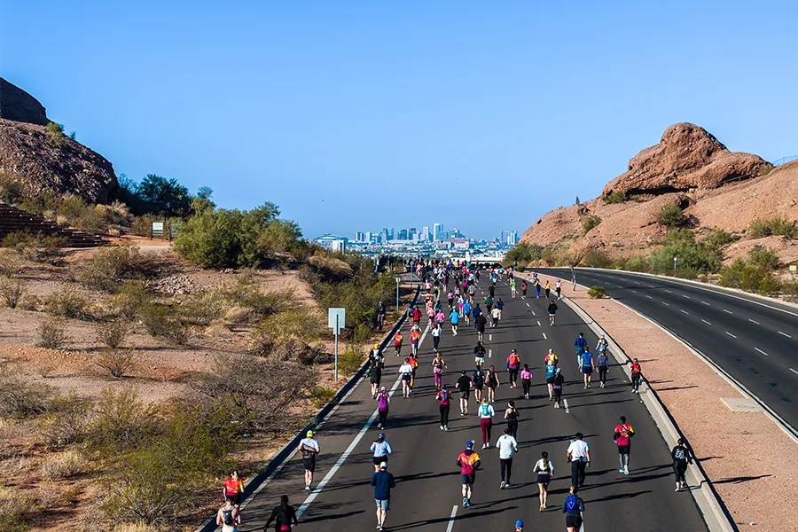 Runners on a road with the Phoenix skyline in the distance during the Rock 'n' Roll Arizona Marathon.