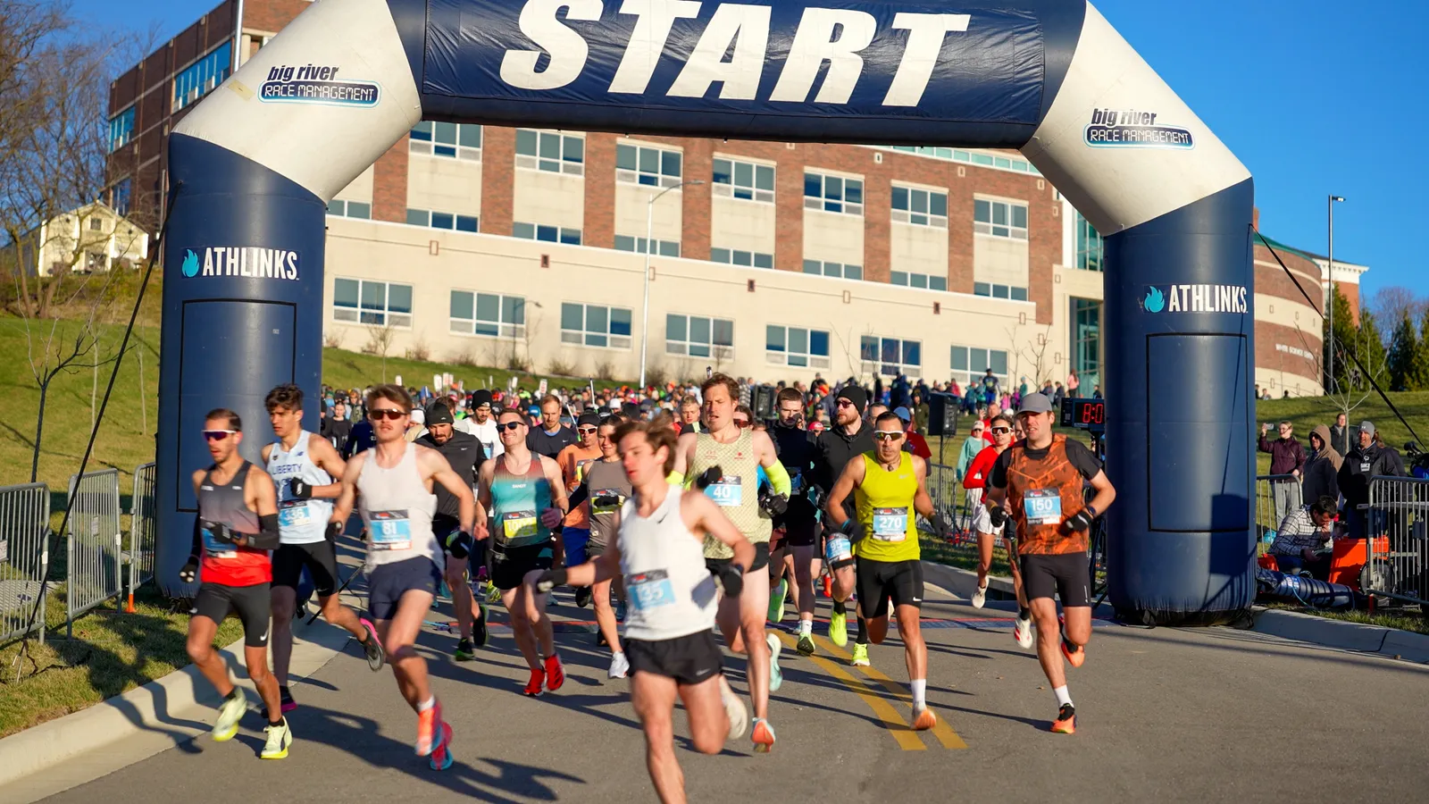 Runners crossing the start line under a large inflatable arch with 'START' written across it.