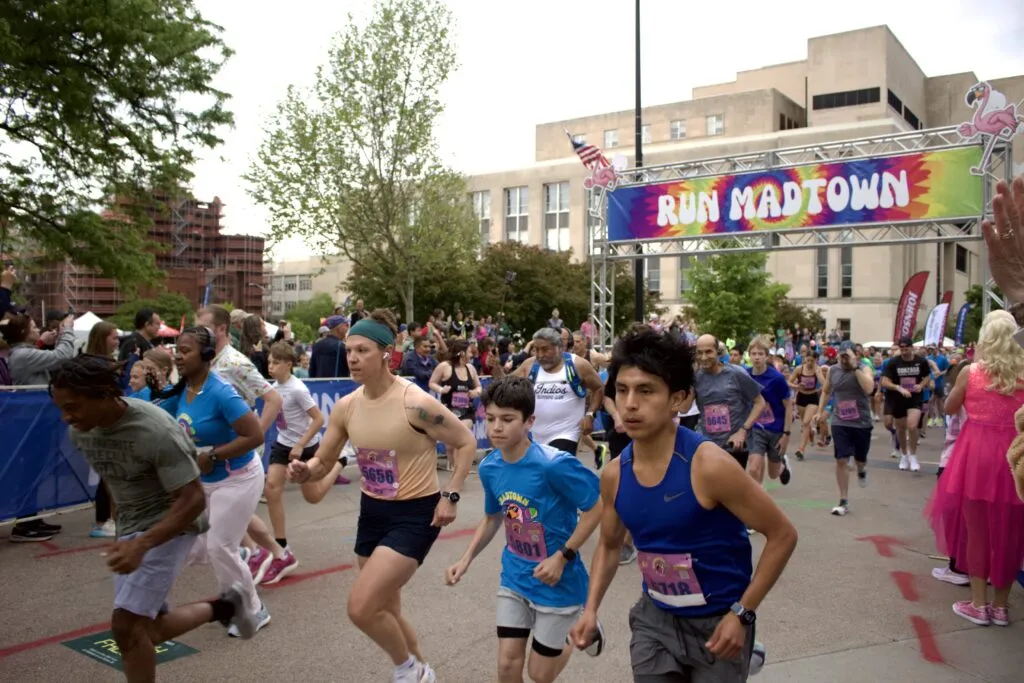 Runners starting the Run Madtown race under a colorful banner.
