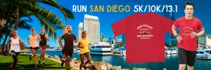 Runners participating in the Run San Diego 5K/10K/13.1 race along a scenic waterfront with city skyline in the background.
